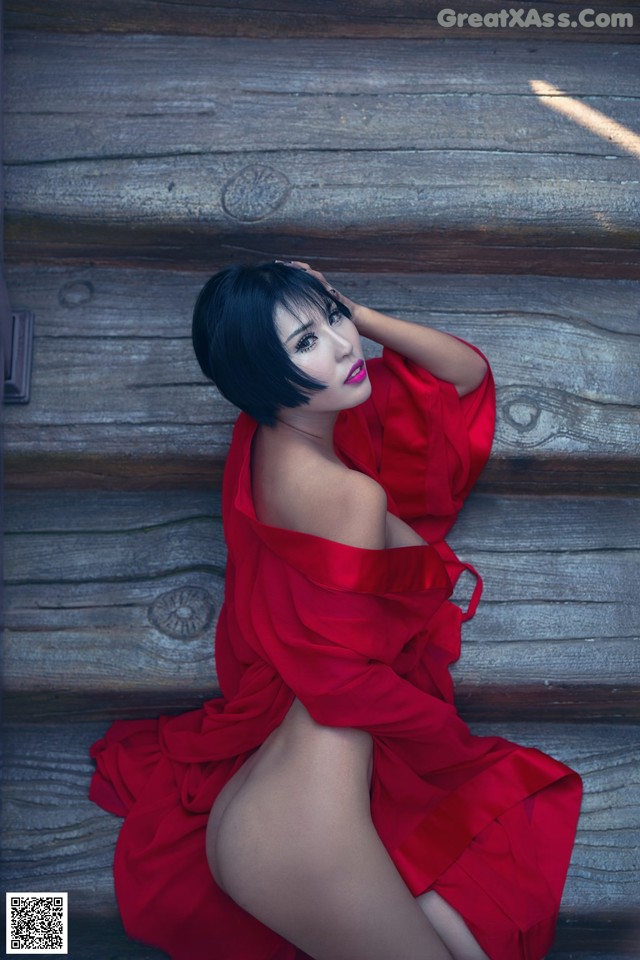 A woman in a red dress sitting on a wooden bench.