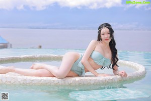 A woman in a bikini posing in front of a palm tree.