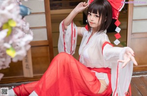 A woman in a red and white kimono sitting on a bench.