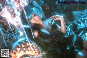 A woman with long blue hair sitting on a rock.