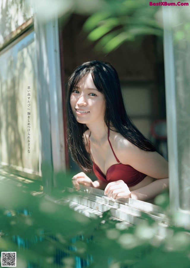 A woman in a red bikini looking out of a window.