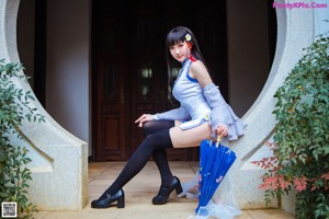 A woman in a blue and white dress holding an umbrella.