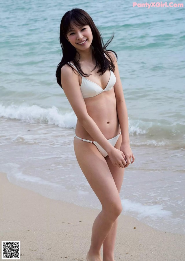 A woman in a white bikini standing on a beach.