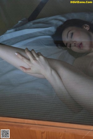 A naked woman laying on a bed with her back to the camera.