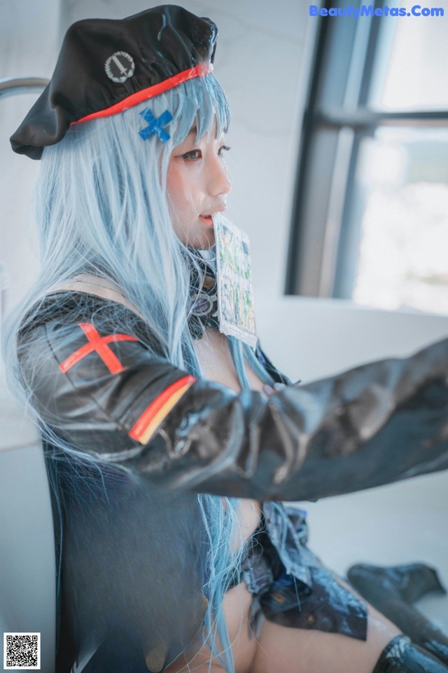 A woman with blue hair wearing a black hat and leather jacket.