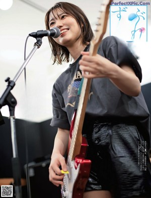 A woman playing a red electric guitar in a magazine.