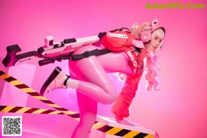 A woman in a pink outfit sitting on top of a white box.