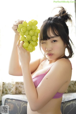 A woman in a pink bikini holding a glass of orange juice.