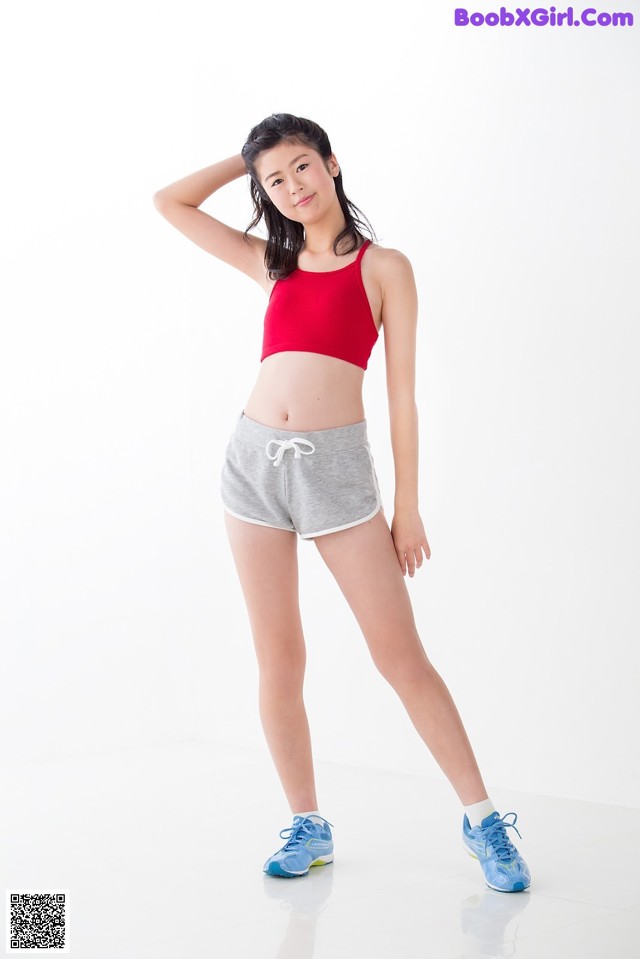 A woman in a red top and gray shorts posing for a picture.