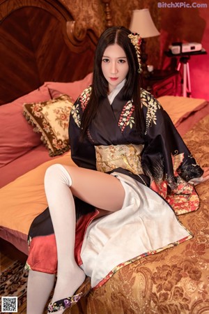A woman in a white bikini sitting on a bed.