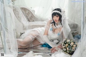 A woman in a wedding dress sitting on a bed.