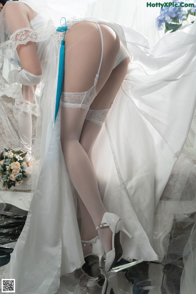 A woman in a wedding dress and stockings posing for a picture.