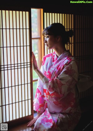 A woman in a pink kimono laying on the floor.