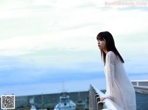 A woman in a white tank top leaning on a table.