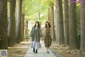 Two young women sitting on a wooden deck in a garden.