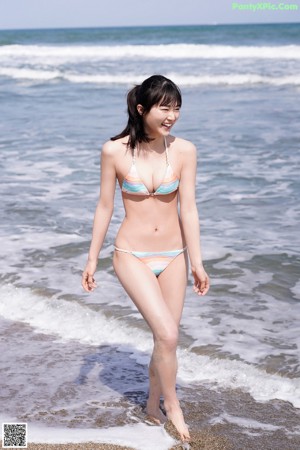 A woman in a bikini sitting on the beach.