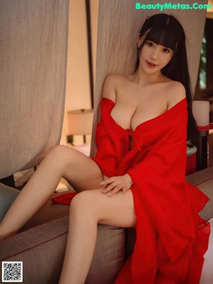 A woman in a red robe sitting on a window sill.