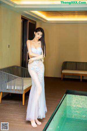 A woman in a white dress sitting on a metal railing.