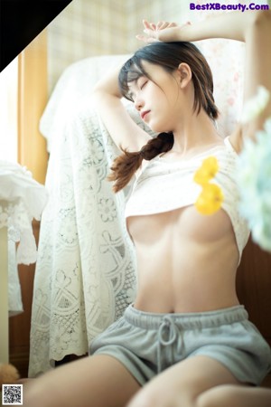A naked woman sitting on top of a bed next to a window.