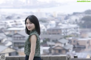 A woman standing on top of a balcony next to a railing.