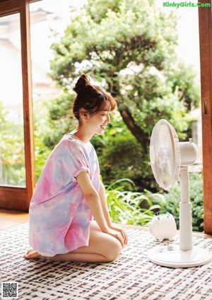 A young woman sitting in front of a fan.