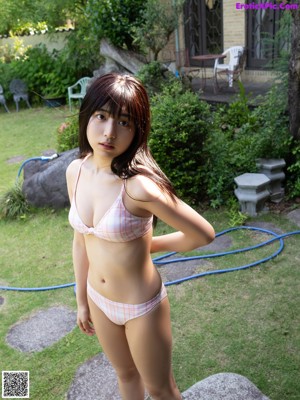 A woman in a white bikini standing in a kitchen.