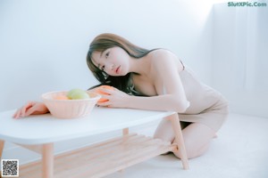 A woman sitting at a table with a bowl of fruit.