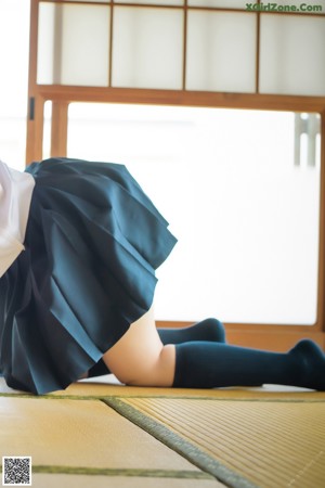 A woman in a school uniform sitting on the floor.