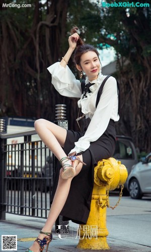 a woman in a white shirt and black skirt is walking down the street