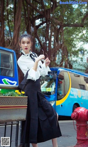 A woman in a blue shirt and white skirt posing for a picture.