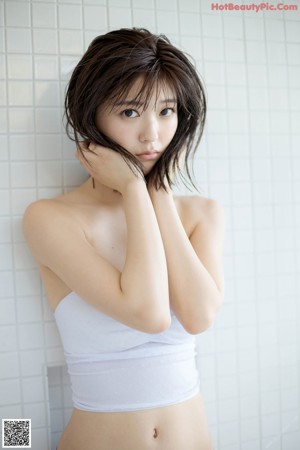 A woman in a blue bra sitting in a bathtub.
