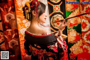 A woman in a kimono holding an umbrella in a city street.