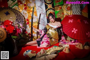 A woman in a kimono holding an umbrella on a city street.