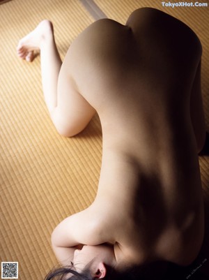 A nude woman laying down on a wooden table.