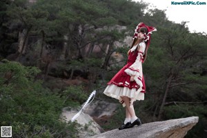 A woman in a red and white dress laying on a rock.