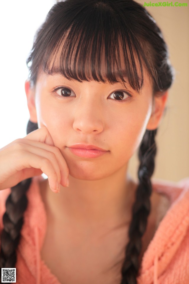 A young woman with long black hair and a pink sweater.