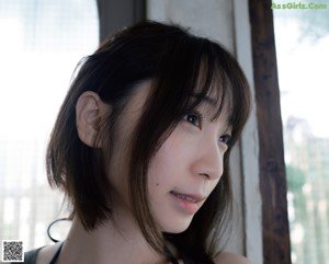 A woman in a black bikini leaning against a wall.