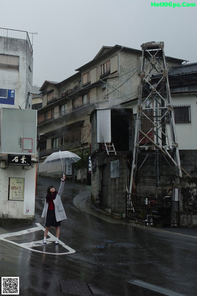 A woman holding an umbrella standing in the middle of a street.