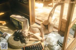 A woman in a white shirt and panties sitting on the floor.