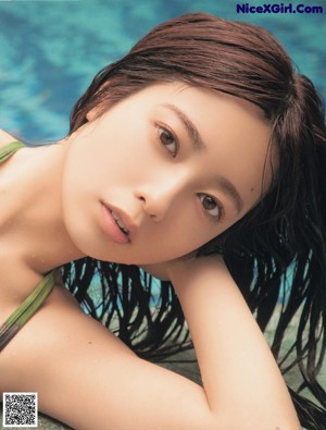 A woman in a bikini laying on the edge of a pool.