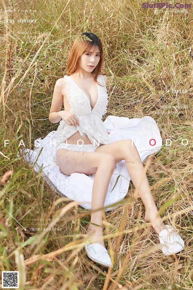 A woman in a white dress sitting in a field of tall grass.