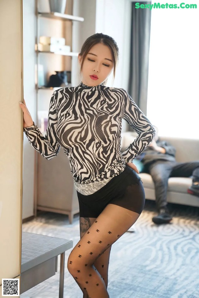 A woman in a zebra print top and black tights posing for the camera.