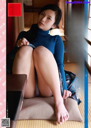 a japanese woman in a blue sweater is sitting on a couch