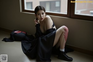 A woman sitting on a ledge with her legs crossed.