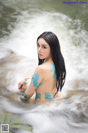 A woman standing in front of a waterfall.