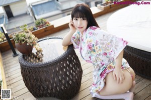 A woman in a white bikini sitting on a wooden deck.