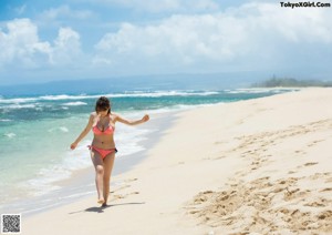 A woman in a white dress is running on the beach.