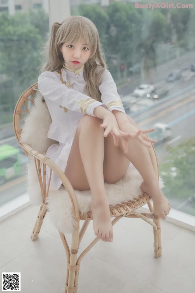 A woman sitting on a chair in front of a window.
