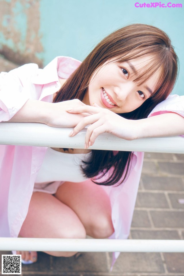 A young woman leaning on a railing with her hand on her chin.