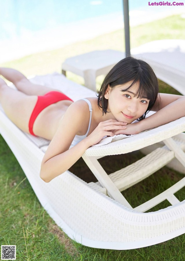 A woman in a red bikini laying on a white lounge chair.